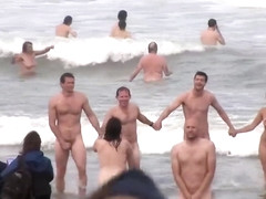 Hundreds of nudist people running into the sea naked